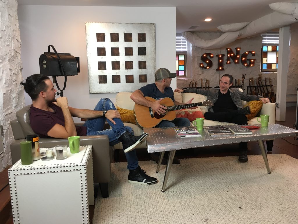 Three guys talking holding guitar