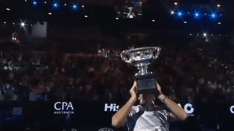 An animated gif of a guy holding up a trophy in an arena
