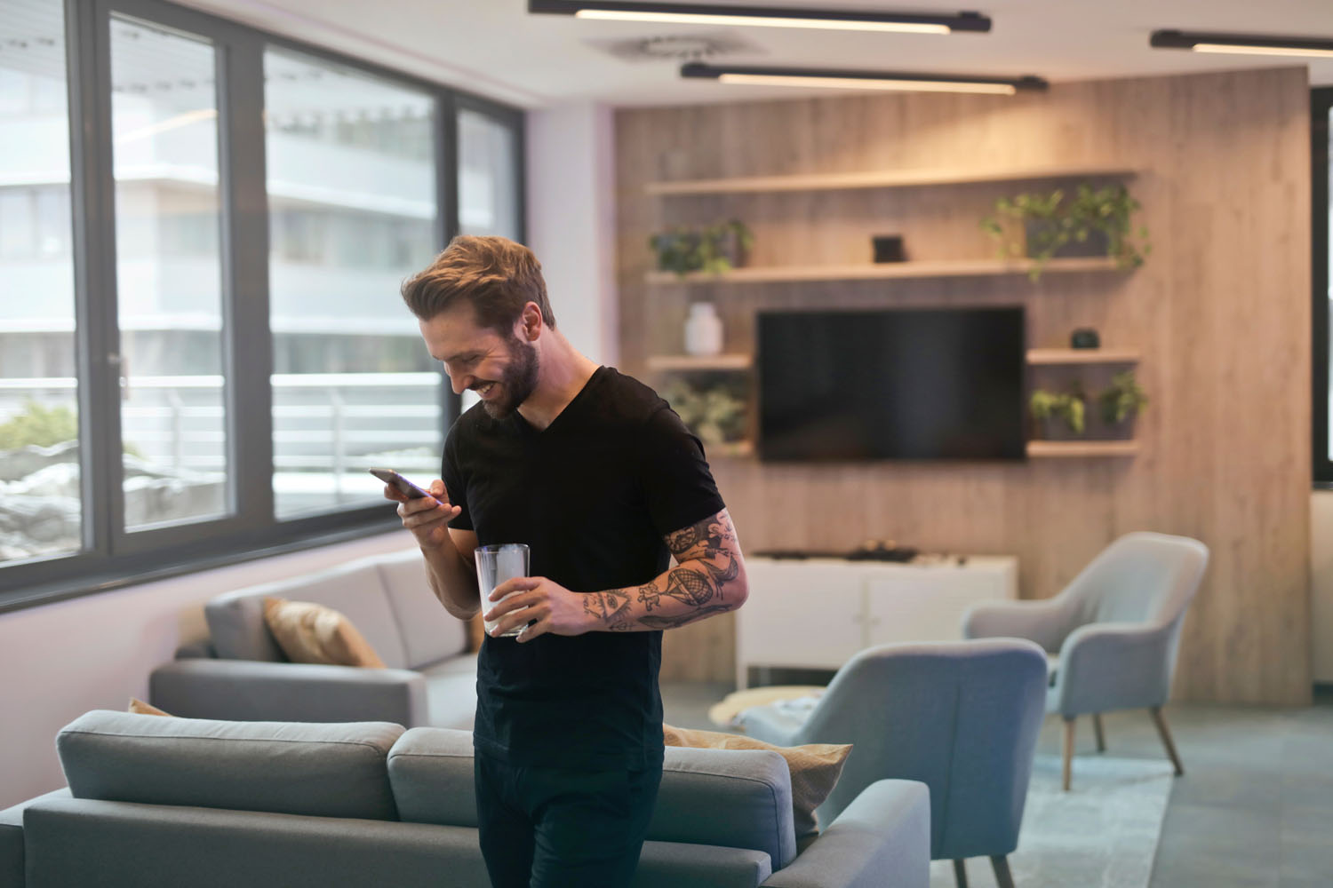 Image of man drinking coffee and laughing while looking at his phone community management..