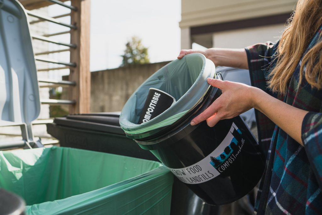an office compost bin being dumped into a larger compost receptacle