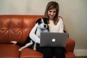 A dog leaning on a woman working on a laptop