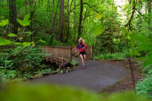 girl running on trail with dog