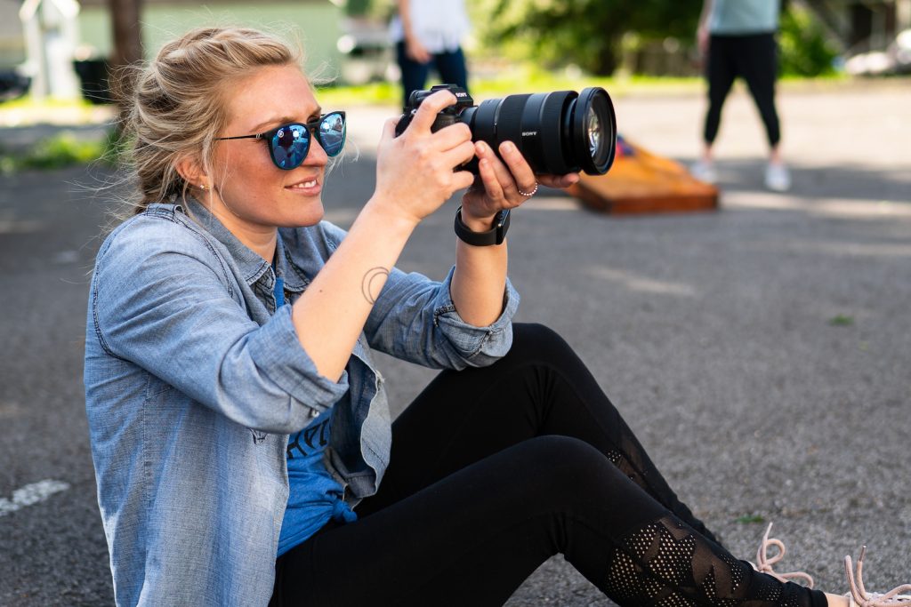 girl sitting down and taking a picture with a camera