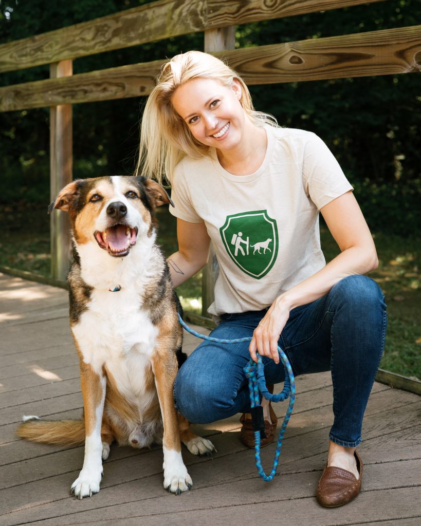 An image of a girl wearing a Camping With Dogs t-shirt and smiling with her dog.