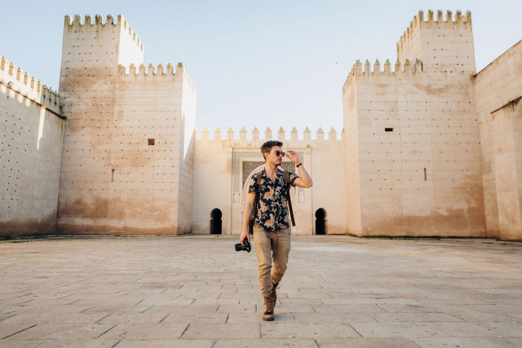 Image of man walking through a softly-lit court yard in Morocco with a camera in hand.