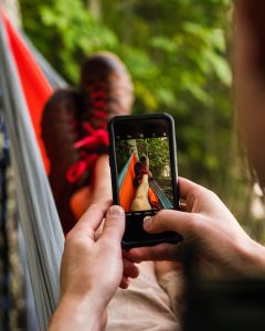 An image of a man in a hammock with a phone taking a picture