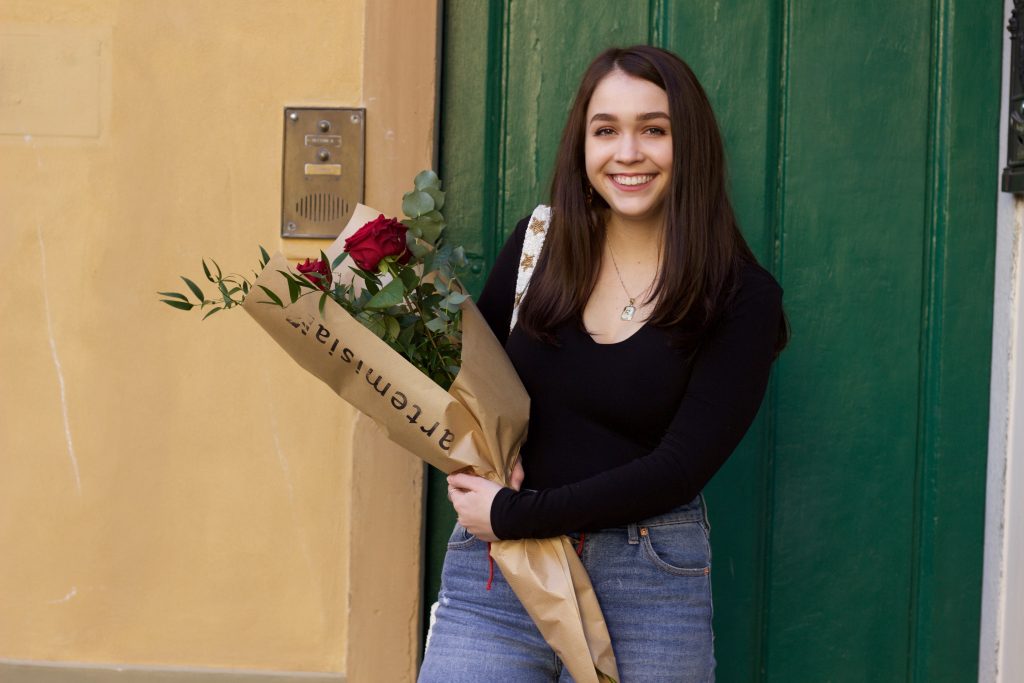 Rileigh holding a boquet of flowers in front of a green door.